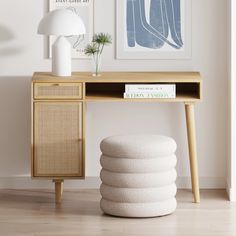 a wooden table topped with a white lamp next to a shelf filled with books and magazines