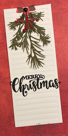 a piece of paper with the words merry christmas written on it and a pine branch