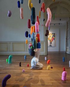 an art installation with various colored objects floating in the air and on top of a wooden floor