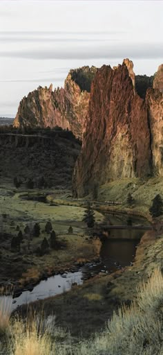 the mountains are covered in green grass and brown rocks, with a river running between them