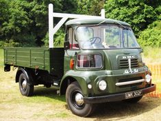 an old green truck is parked in the grass