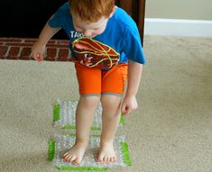 a young boy standing on top of a green and white object in front of a door