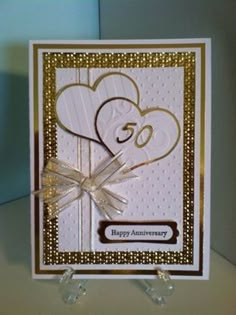 a white and gold anniversary card with two hearts on it's side, tied in a bow