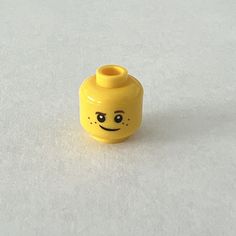 a small yellow vase with a smiley face on it's side, sitting on a white surface