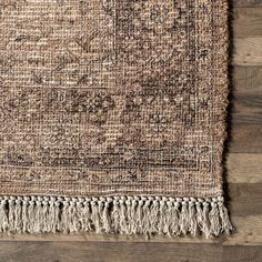 an area rug with fringes on top of it and wood flooring in the background