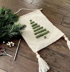 a crocheted christmas tree decoration on a wooden floor next to scissors and needles