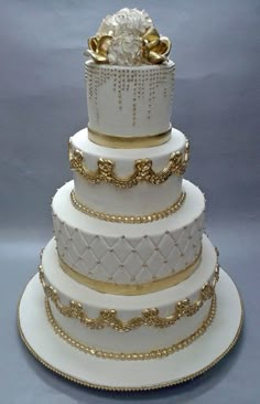 a three tiered wedding cake with gold decorations