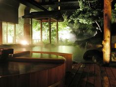 an outdoor hot tub at night with lights shining on the water and trees in the background