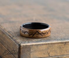 a wooden ring with mountains on it sitting on top of an old wood box,