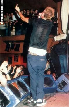 a man standing on top of a stage with his arms in the air and hands raised