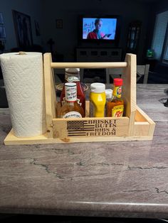 a wooden tray with condiments in it on a counter top next to a television