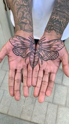 a man with tattoos on his hands holding a bee tattoo in front of his hand