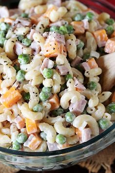 a glass bowl filled with pasta salad on top of a table