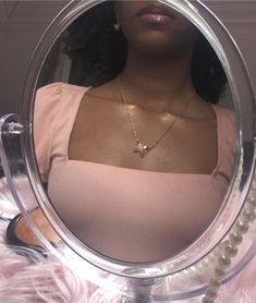 a woman is looking into a mirror with pearls on the bottom and necklaces hanging from it