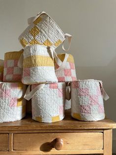 a pile of quilted baskets sitting on top of a wooden table next to a drawer