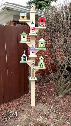 a tall birdhouse with many birds on it's sides in front of a fence