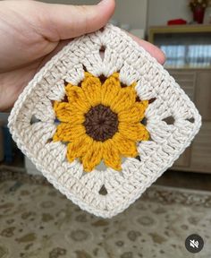 a crocheted square with a sunflower on it in someone's hand