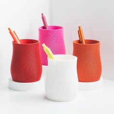 three different colored cups with pencils in them and one has a yellow toothbrush holder