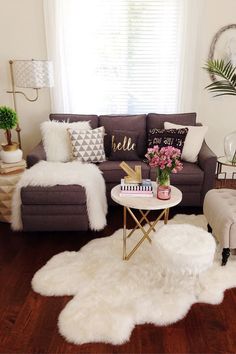 a living room with white fur rugs on the floor and furniture in front of a window