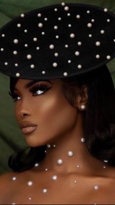 a woman wearing a black hat with white pearls on the top and side of her head