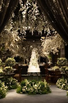 the wedding cake is surrounded by white flowers and greenery in front of an open dining room