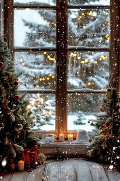 two christmas trees sitting in front of a window with snow falling on the windowsill