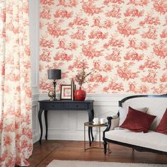 a living room with red and white wallpaper, a couch and table in front of the window