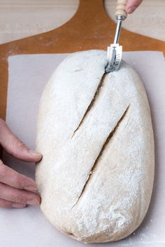 a person cutting bread with a knife on top of it