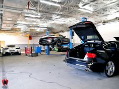 two cars are parked in a garage with their hoods open and the back doors open