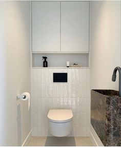 a white toilet sitting inside of a bathroom next to a wall mounted faucet