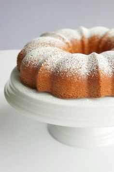 a bundt cake with powdered sugar on top is sitting on a white pedestal