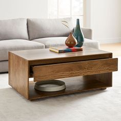 a living room with a couch, coffee table and books on the end tables in front of it