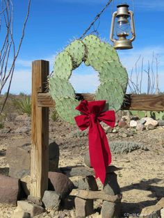 a cactus wreath with a red bow hanging on a wooden post