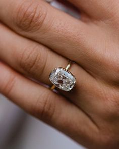 a woman's hand holding an engagement ring with a large diamond in the center