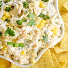 a white bowl filled with corn salad surrounded by tortilla chips