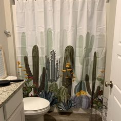 a bathroom with a cactus shower curtain next to a toilet