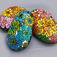 three painted rocks with flowers on them