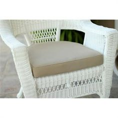 a white wicker chair with a cushion on the back and seat cushions in front of it