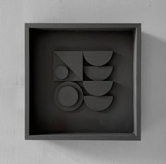 a black box with shapes in it on a white wall and the bottom half is cut out