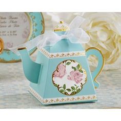 a teapot shaped box with a bow on the top and flowers painted on it