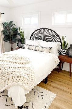 a bed with white blankets and pillows on top of it in a bedroom next to a window