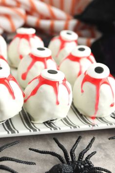 some white and red cake balls on a plate with black spider webs around them