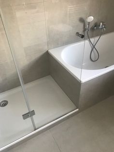 a white bath tub sitting next to a walk in shower under a faucet