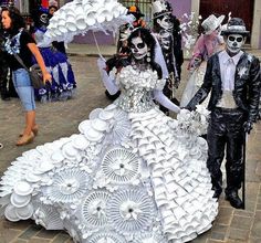 a man and woman dressed up as skeletons with paper plates on their heads walking down the street