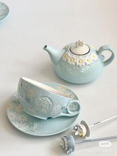 two tea cups and saucers are sitting on a white table with spoons next to them