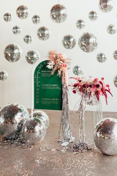 disco balls and vases on a table in front of a sign