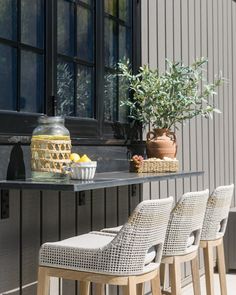 four chairs are lined up outside near a table and potted plant with lemons on it