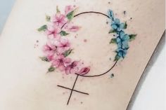 a tattoo with pink flowers on the side of a woman's thigh and cross