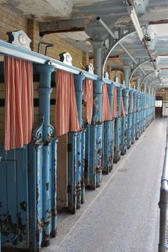 the inside of an old building with blue pipes and orange towels hanging from them