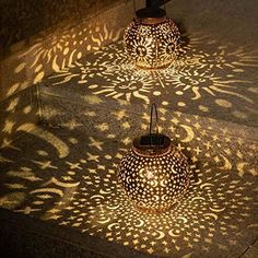 three lit candles sitting on top of a wooden table next to a wall with an intricate design